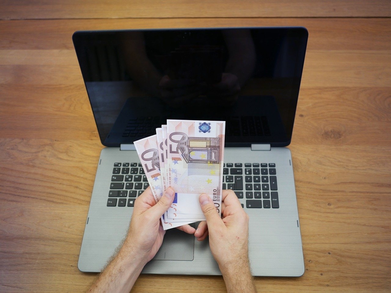Man counting money in front of laptop